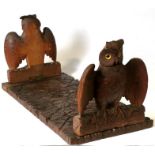 A 19th century Black Forest bookslide, carved with a pair of owls with outswept wings, perched on