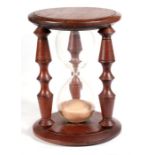 A mahogany hourglass timer, 18cm high.