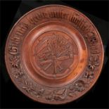 A Black Forest bread board, carved with flowers and central wheat sheaf, 33cm diameter.