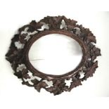 A Black Forest picture frame with carved flowers, leaves and berry decoration, 29cm x 34cm.