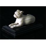 An 18th century carved ivory figure of a recumbent dog, mounted on a stepped horn base, 6cm long.