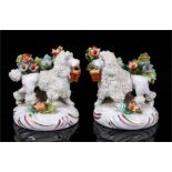 A pair of Sitzendorf figures modelled as poodles holding baskets with flowers, 6cm high.