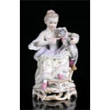 An early 19th century Meissen figure in the form of a young girl seated feeding a cat, blue