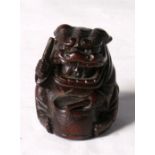 A Japanese carved hardwood netsuke in the form of a boy wearing a lion suit and playing a drum,