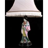 A Japanese porcelain figural table lamp in the form of a woman wearing a pink robe reading a scroll,