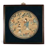 A Chinese embroidered circular silk panel depicting a lady and two children within a foliate border,