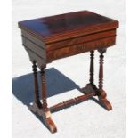 A figured mahogany swivel top games table, the fold-over top above a single frieze drawer, on turned