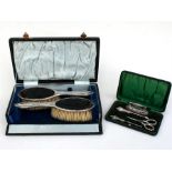 A cased silver manicure set, Birmingham 1909, together with a pair of cased silver brushes.