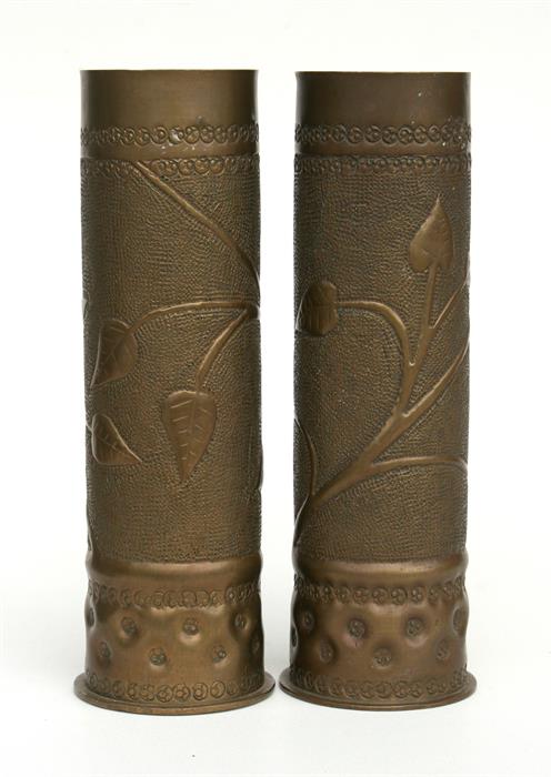 A matching pair of WWI trench art shell case vases decorated with foliage, 27.5 by 9cms.