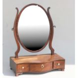 A 19th century figured mahogany toilet mirror, the oval mirror above three drawers, 43cm (17ins)