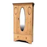 A stripped pine single wardrobe, the single oval mirrored door above a long drawer, 92cm (36ins)