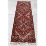An Indian khandahar runner rug with central medallions on a red ground. 88cm by 276cm ( 30 by 108.
