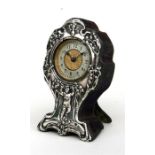 An Edwardian silver mounted clock, the embossed decoration of a small child and Lily of the Valley