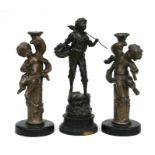 A spelter figure 'Au Pressoir', 38cm (15ins) high; together with a pair of cherub candlesticks (3).