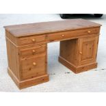 A modern pine pedestal desk with a combination of drawers and cupboards, 150cm (58ins) wide.