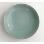 A Chinese celadon glazed shallow saucer dish with fluted decoration, 18.5cm (7.25ins) diameter.