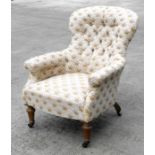 A Victorian button back armchair with turned front legs.