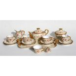 A Limoges part teaset decorated with gilded flowers on a pale blush ground.