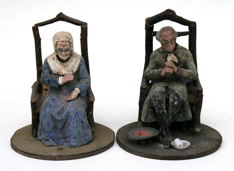 A pair of 19th century nodding figures, modelled as an old man and an old lady sat in rustic chairs,