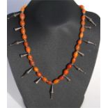 An amber bead necklace, thirty three oval amber beads interspersed by white metal drops, total