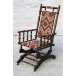 An early 20th century American walnut rocking chair with upholstered seat and back, on turned
