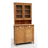 A stripped pine dresser with a pair of glazed doors enclosing a shelved interior, above two short