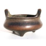 A Chinese bronze two-handled tripod censer of compressed squat form, six character impressed mark to
