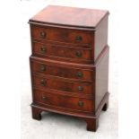 A reproduction mahogany bowfronted miniature chest with five long graduated drawers, standing on