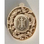 An early 20th century Chinese pierced and carved ivory pendant, the central character within a