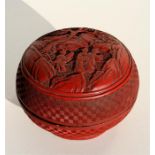 A Chinese cinneber lacquer circular box and cover, the top decorated with figures under a tree in