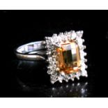 An 18ct white gold ring, the central square cut yellow stone (possibly a yellow sapphire) surrounded