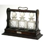 An late 19th / early 20th century oak three-bottle Tantalus (lacks key).