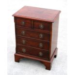 A reproduction yew wood miniature chest, with two short and three long drawers, standing on