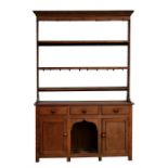 A 19th century Welsh oak dog kennel dresser having an open three shelf rack under a moulded cornice,