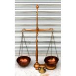 A set of balance scales with copper pans and graduated brass weights.