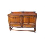 An oak sideboard, the pair of panelled doors above two drawers, on turned legs joined by stretchers,