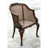 A walnut bergere tub chair on cabriole front supports.