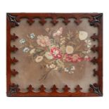 A 19th century woolwork panel depicting a spray of flowers, in an ornate rosewood frame, 34 by