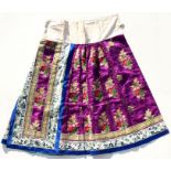 A Chinese silk skirt embroidered with repeat flower design on a purple ground within figural