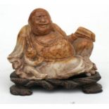 A Chinese soapstone carving in the form of a seated Buddha with a child; on a hardwood stand, 8cm (