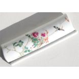A Chinese famille rose wrist or brush rest, decorated with birds and flowers, 17cm (6.75ins) wide.