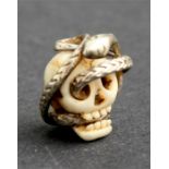A Japanese silver mounted hand carved Ojime bead, in the form of a skull with an entwined snake, 2cm