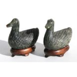 A pair of Chinese carved jade like ducks on hardwood stands, 9cm (3.5ins) high.