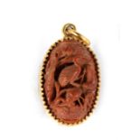 An 18ct gold mounted Chinese carved nut pendant, deeply carved with birds in a landscape, 2.5cms (