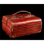 A crocodile skin case containing silver top dressing table jars, ivory brushes and shoe horn. The