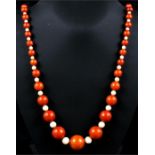 An amber coloured and mother of pearl bead necklace, 74cms (29ins) long, the largest bead 22mm