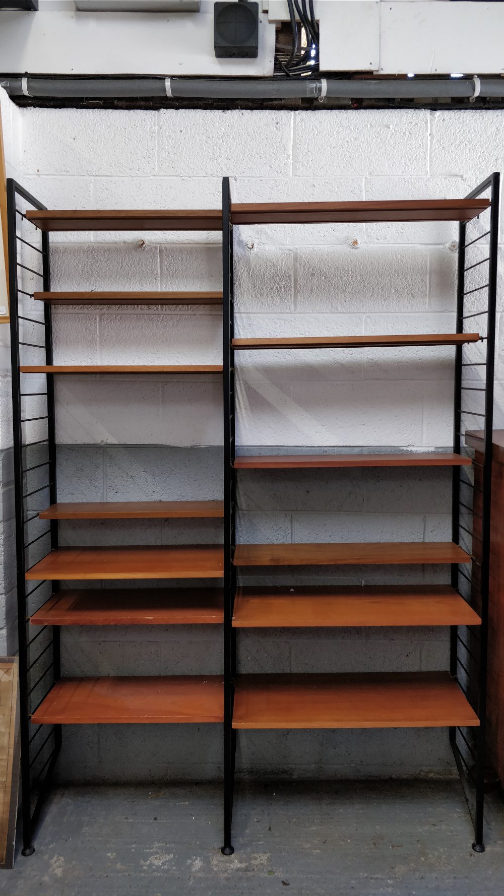 A 1970's ladder shelving unit, with 12 adjustable shelves, 221cm high, 140cm wide, 35cm deep