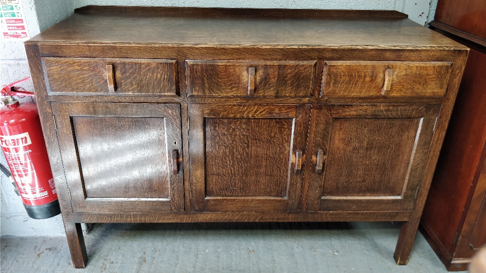 A 1930's oak sideboard, with two fitted cupboard sections and two fitted drawers by Heal's of