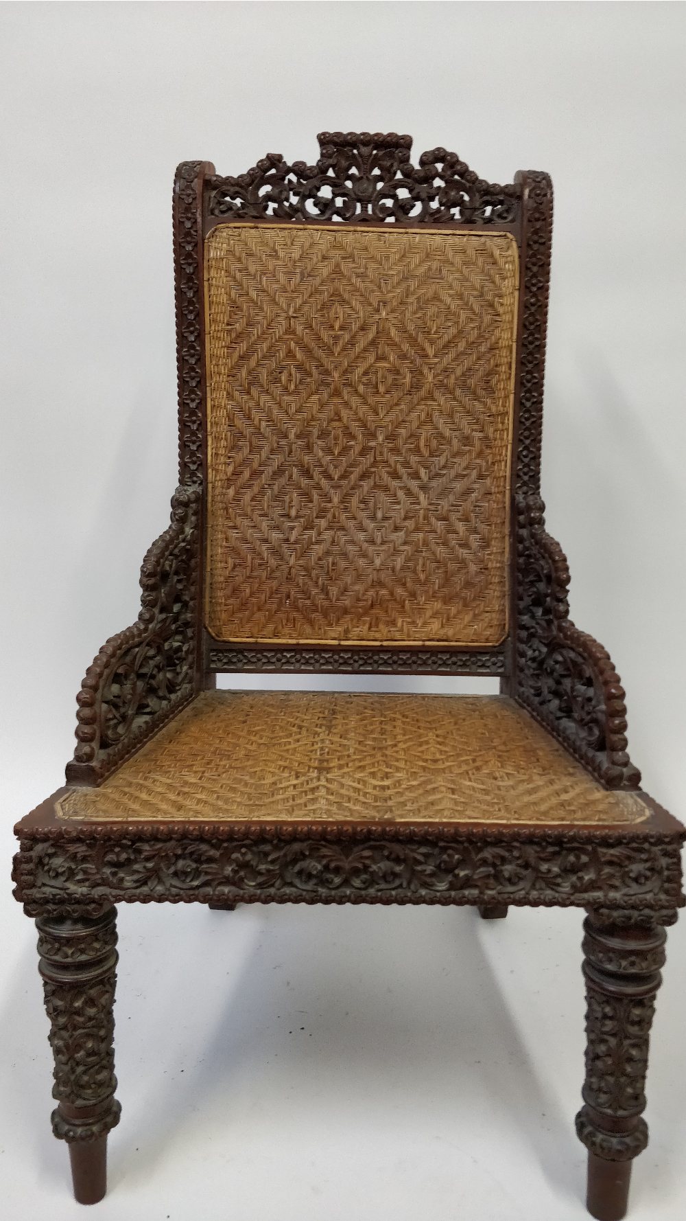 A 19th century Anglo Indian carved hardwood chair with a wicker seat and back