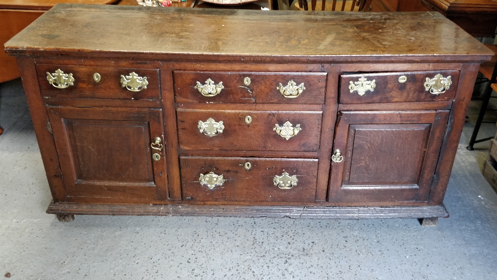 A 18th century oak dresser base, with fitted two cupboard section, three central short drawers and